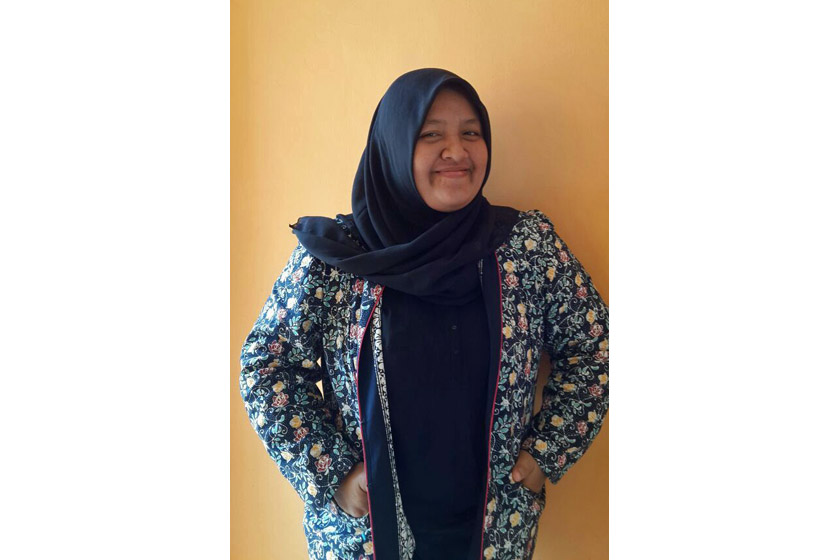 A woman with blue hijab and batik dress smiling